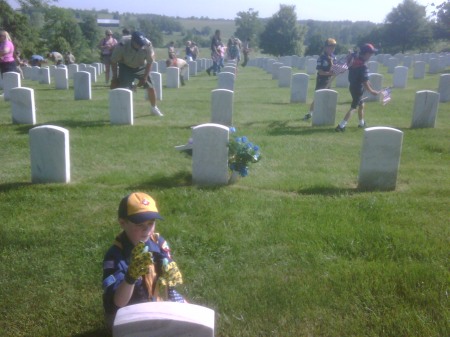 Colby placing a flag at one of the grave sites at Camp Nelson